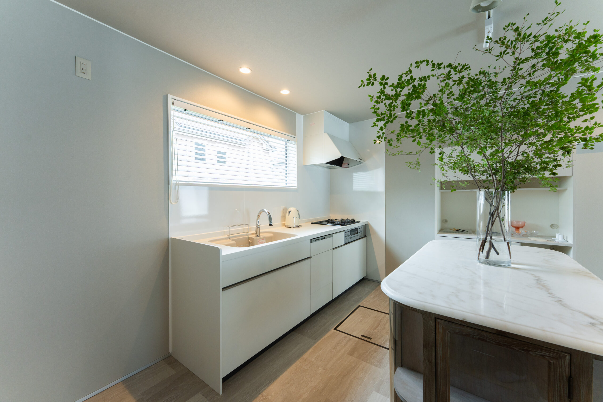 T邸キッチン詳細 — 白い設備と枝物のグリーン