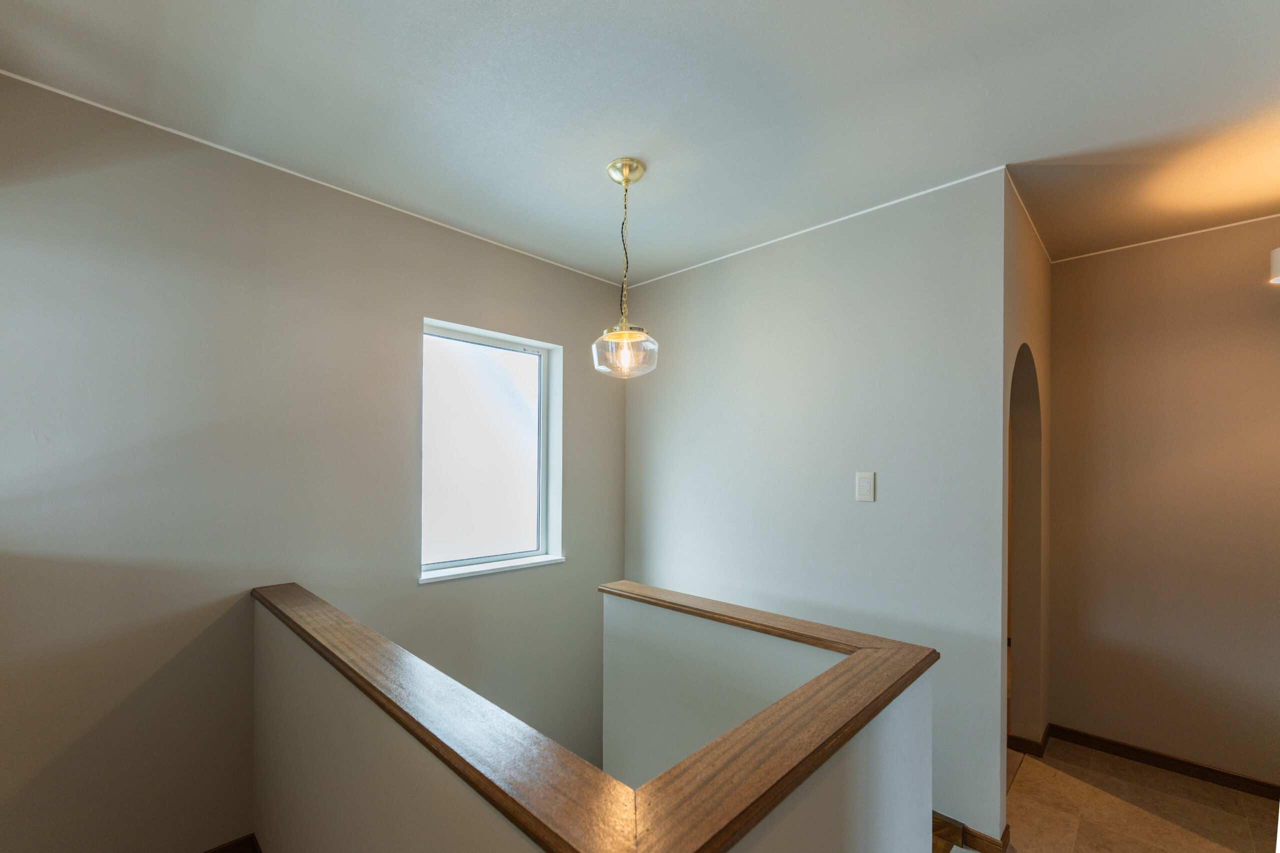 T邸階段ホール — ペンダントライトとアーチ開口